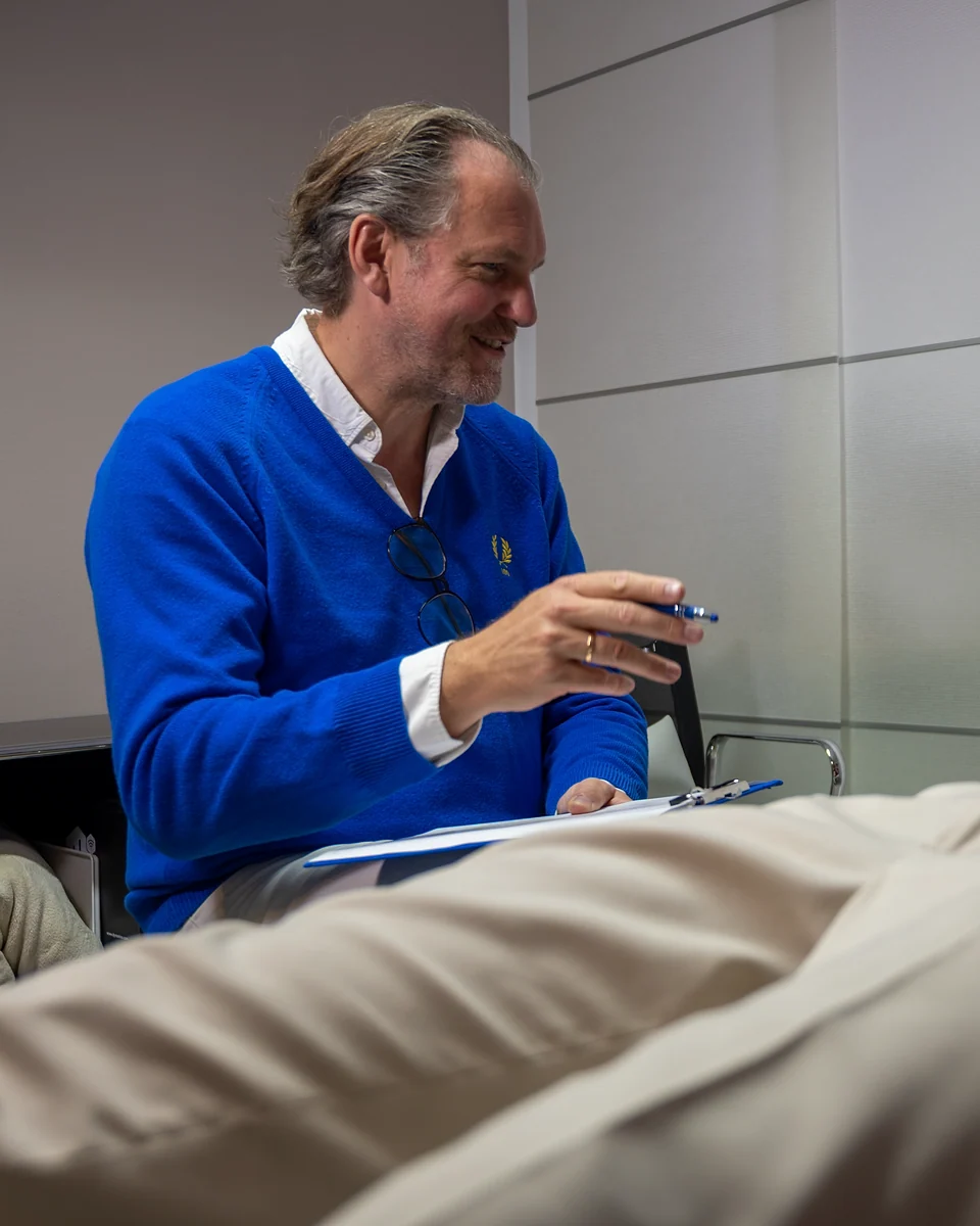 Dr. Meschede im Gespräch mit einer Patientin, lächelnd mit Klemmbrett in der Hand