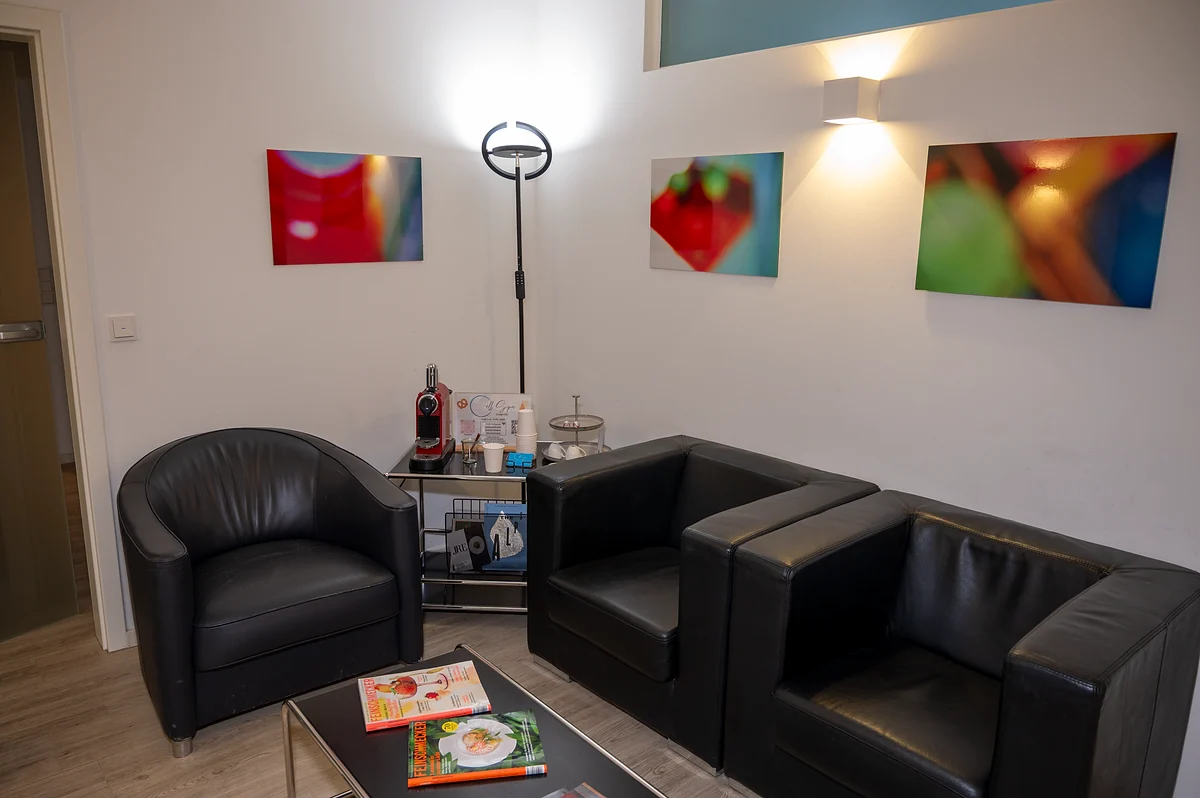 Lounge der Praxis mit Ledersesseln und Kunst an der Wand